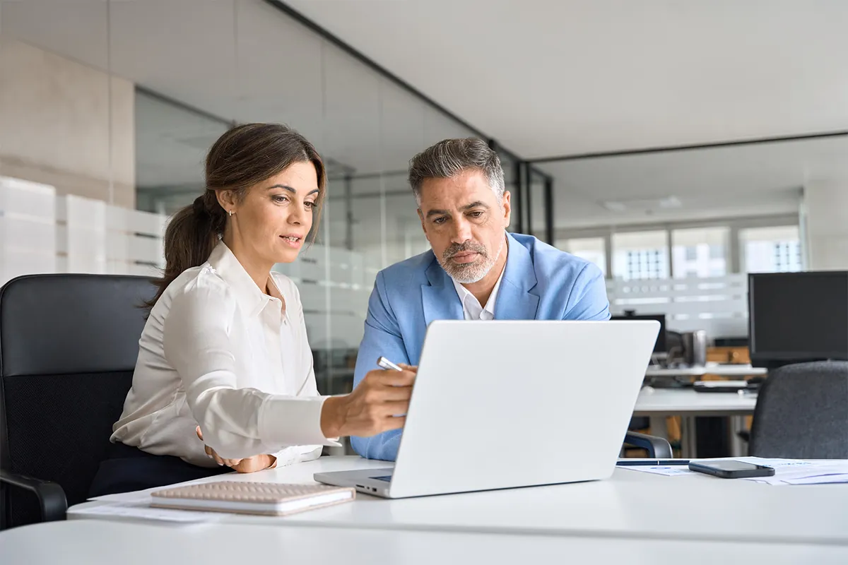 Two colleagues reviewing work together on a laptop in an office