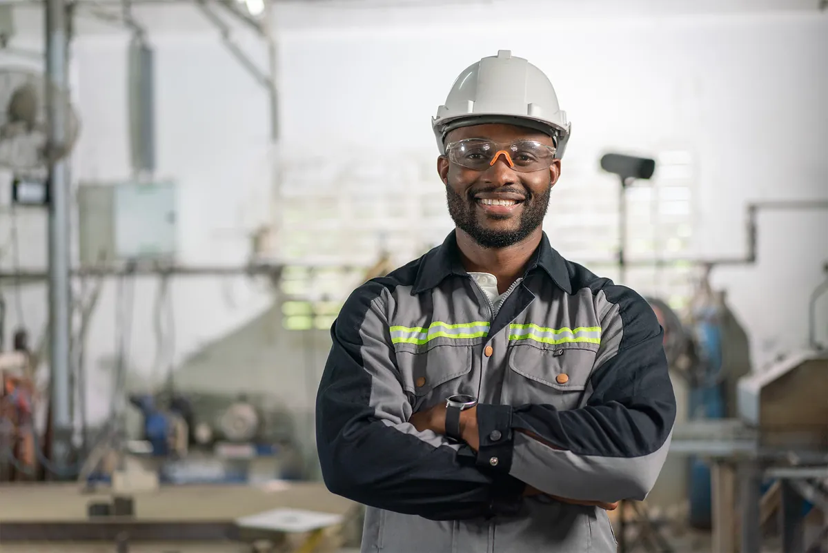 Smiling worker in a hard hat and safety glasses in an industrial facility